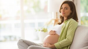 Mujer embarazada descansando en casa, imagen para seguro de salud Caser embarazo